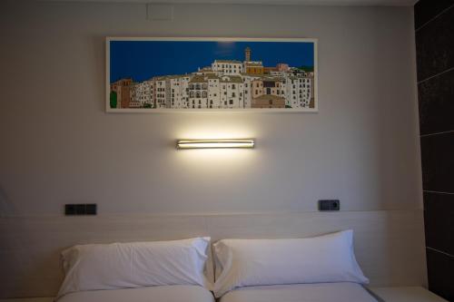 a picture hanging above a bed with white pillows at Hotel LB Villa De Cuenca in Cuenca