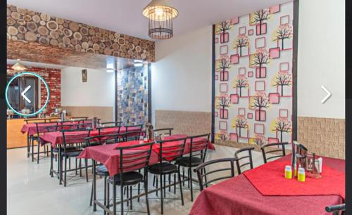 a restaurant with red tables and chairs and a wall at Hotel Prince in Manāli