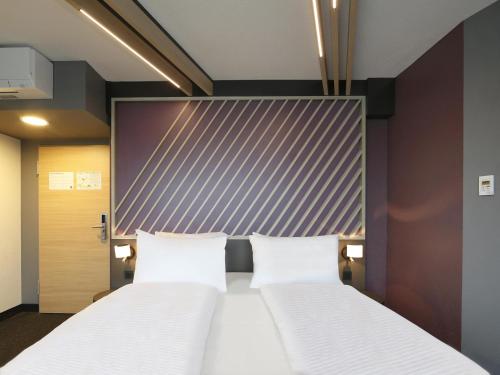 2 Betten in einem Hotelzimmer mit Kopfteil in der Unterkunft B&B Hotel Berlin City-West in Berlin