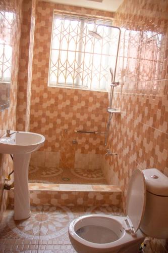 a bathroom with a shower and a toilet and a sink at Maakyere Apartments in Kintampo