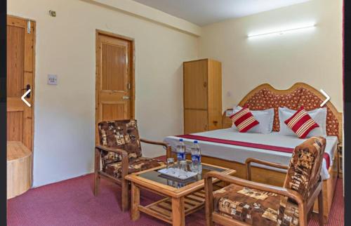 a bedroom with a bed and two chairs and a table at Hotel Prince in Manāli