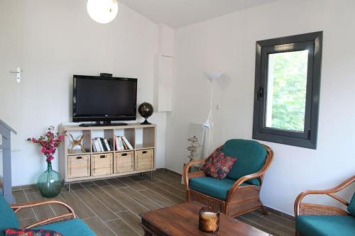 a living room with a flat screen tv and chairs at Charmante Maison Basque - 15min à pieds des plages - 6 Personnes in Guéthary