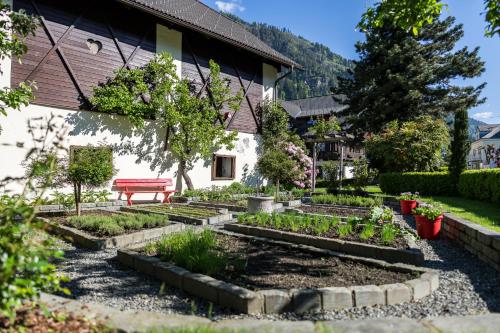 a garden in front of a building with a red bench at Familiengut Hotel Burgstaller in Döbriach