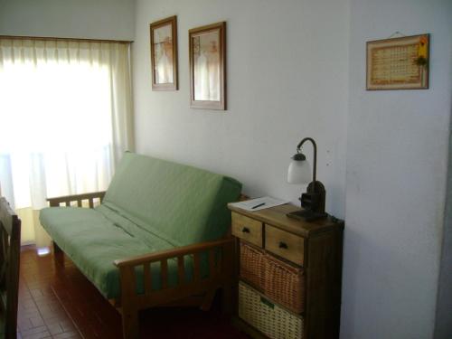 a bedroom with a green bed with a lamp on a dresser at Apartamento Del Mar in Mar del Plata