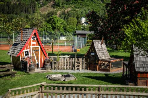 a playground with a small red house and a play yard at Familiengut Hotel Burgstaller in Döbriach