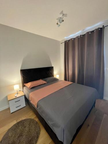 Schlafzimmer mit einem Bett und einem Fenster mit Vorhängen in der Unterkunft 1 bedroom cosy apartment in Tivat