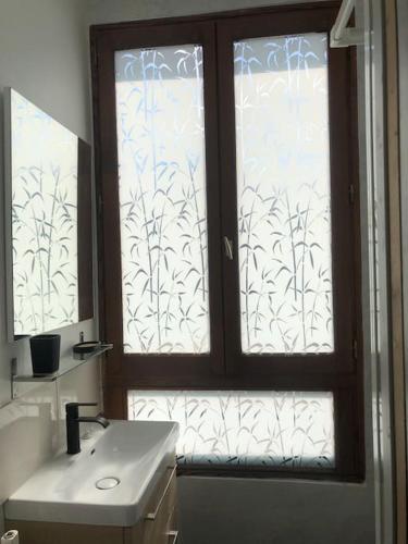 La salle de bains est pourvue d'une fenêtre avec un lavabo et un miroir. dans l'établissement Le jardin d'Alfortville, à Alfortville