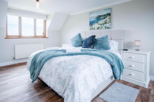 a bedroom with a bed with a blue and white comforter at Highfield - 5 Bedroom Holiday Home - Pembroke Dock in Pembroke Dock