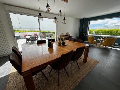 - une table à manger et des chaises dans le salon dans l'établissement Entre Terre et Mer 12 Personnes Espace Piscine chauffée, à Landivisiau