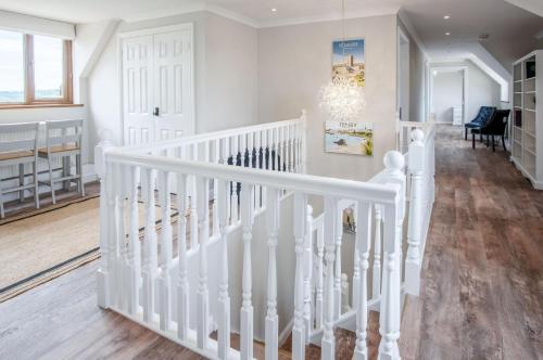 a white staircase in a living room with a chandelier at Highfield - 5 Bedroom Holiday Home - Pembroke Dock in Pembroke Dock