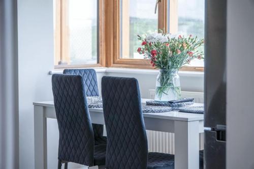 a table with two chairs and a vase of flowers at Highfield - 5 Bedroom Holiday Home - Pembroke Dock in Pembroke Dock