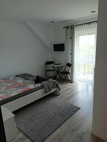 a white bedroom with a bed and a desk at Noclegi U Janusza - Bieszczady in Polańczyk