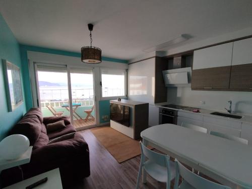 eine Küche und ein Wohnzimmer mit einer Couch und einem Tisch in der Unterkunft Faro da Borneira in Cangas