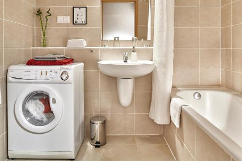 ein Badezimmer mit einer Waschmaschine und einem Waschbecken in der Unterkunft 7Seasons Apartments Budapest in Budapest