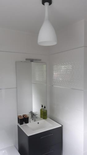 une salle de bain blanche avec un lavabo et un miroir dans l'établissement 1 2 3 Chambres entre la Presqu île de Rhuys et le Golfe du Morbihan, à Theix