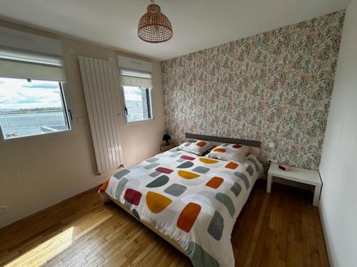 une chambre avec un lit avec une couette colorée dans l'établissement Entre Terre et Mer 12 Personnes Espace Piscine chauffée, à Landivisiau