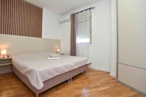 ein weißes Schlafzimmer mit einem Bett und einem Fenster in der Unterkunft Dolami residence in Becici
