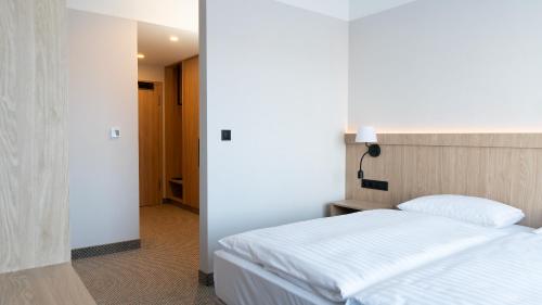 a bedroom with a white bed and a hallway at Hotel Continental in Krynica Morska