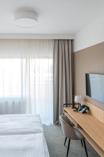 a hotel room with a bed and a desk with a television at Hotel Continental in Krynica Morska