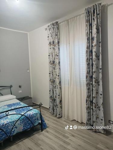 a bedroom with a bed and a window with curtains at Il tramonto in Balestrate