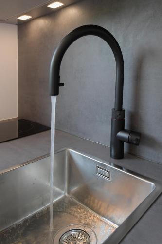 a kitchen sink with water running from a faucet at Hotel und Alpen Apartments mit Sauna - Bürglhöh in Bischofshofen