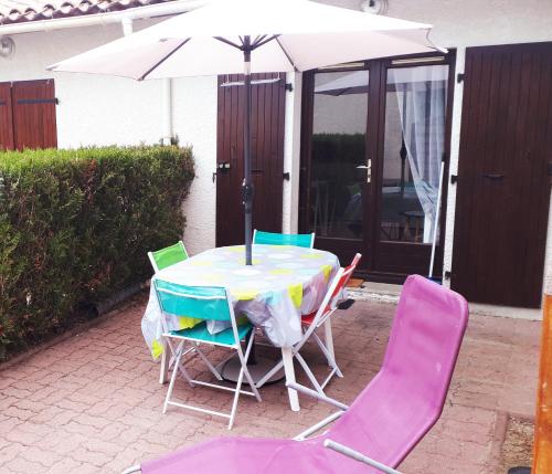 une table et des chaises avec un parasol sur une terrasse dans l'établissement La maisonnette d'Elo - 4 personnes piscine, aux Mathes
