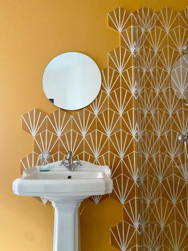 une salle de bain avec un lavabo et un miroir dans l'établissement Villa Baraduc, à Châtel-Guyon