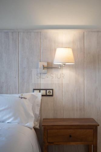 a bedroom with a bed and a table with a lamp at El Gorin Casona in Gijón