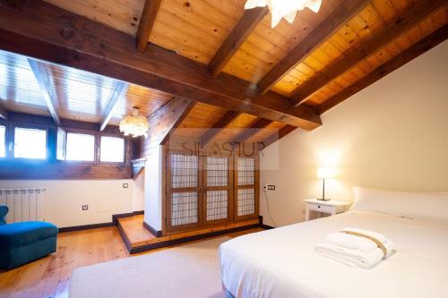 an attic bedroom with a large bed and wooden ceilings at El Gorin Casona in Gijón