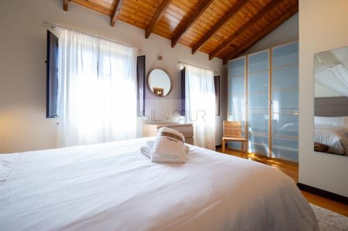 a bedroom with a large white bed with a window at El Gorin Casona in Gijón