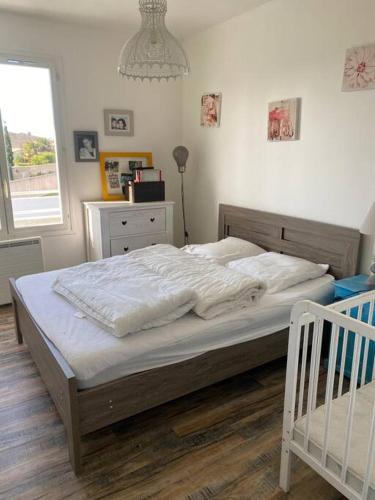 une chambre avec un lit avec des draps blancs et une fenêtre dans l'établissement maison de famille ile de ré 3 étoiles, à Sainte-Marie de Ré