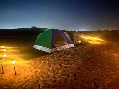 Hunaywah的住宿－Royal Desert Tourism LLC，夜晚沙漠中的一对帐篷