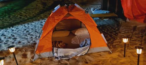 Hunaywah的住宿－Royal Desert Tourism LLC，雪中带灯的橙色帐篷