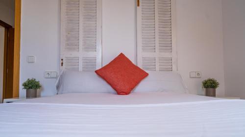 a white bed with a red pillow on it at Houm Villa Samil in Playa de Palma