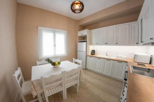 a kitchen with a white table and chairs and a window at Amalia Complex in Nisakion