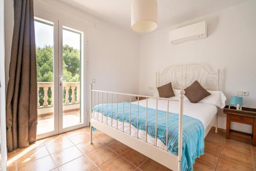 a white bedroom with a bed and a balcony at Houm Villa Samil in Playa de Palma
