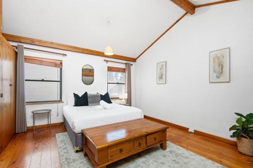 a bedroom with a white bed and a wooden table at 17 Cottesloe - Steps From Beach - Sleeps 2- SUPERHOG REQUIRED in Perth