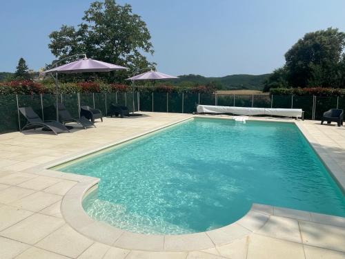 une piscine avec chaises et parasols dans l'établissement Gîtes Les Courrèges, à Vézac