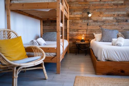 a bedroom with two bunk beds and a chair at Alex Surf Hostel in Baleal