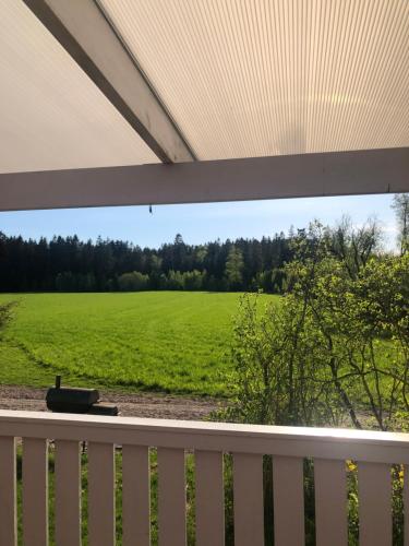 a view of a field from a porch with a fence at Hus i Väse, utanför Karlstad in Väse