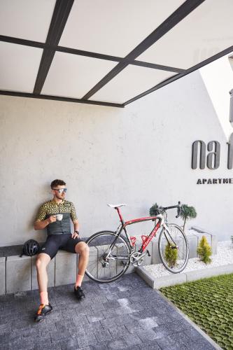 a man sitting on a bench next to a bike at Na Fursie Apartments & Rooms in Nowy Targ