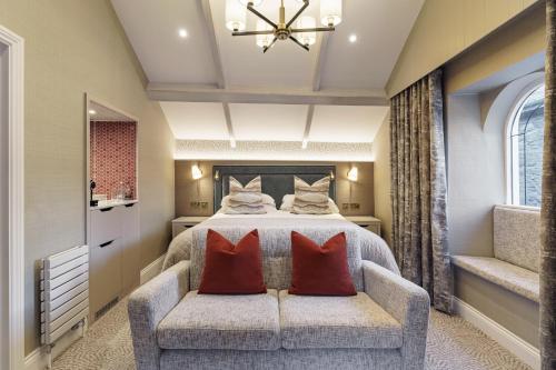 a bedroom with a bed and a couch with red pillows at The Inn On The Lake in Glenridding