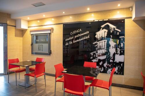 a restaurant with two tables and red chairs at Hotel LB Villa De Cuenca in Cuenca