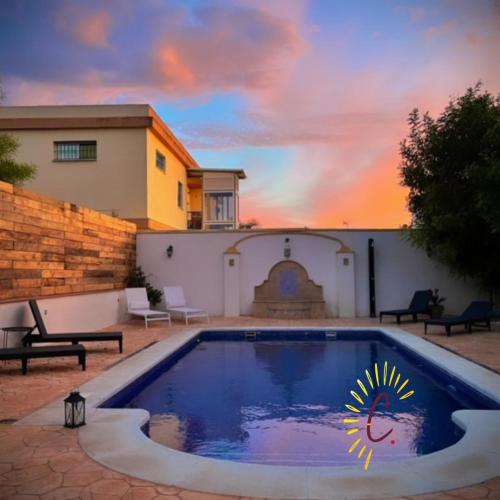 a pool in a yard with a sunset in the background at casa de vicky in El Puerto de Santa María