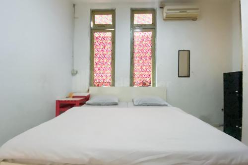 Cama blanca en habitación con 2 ventanas en Wisma Syariah Lambhuk Banda Aceh RedPartner, en Banda Aceh
