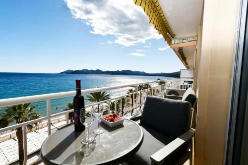 - une table avec des verres à vin et un bol de fruits sur le balcon dans l'établissement Plage du midi- Vue sur mer Standing Presta, à Cannes