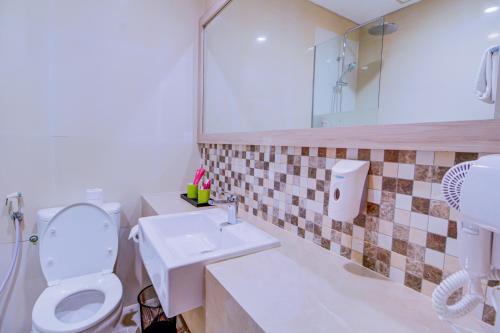 a bathroom with a toilet and a sink at favehotel Gatot Subroto Jakarta in Jakarta