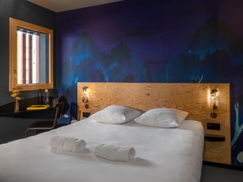 a bed with two white pillows on top of it at Eklo Toulouse in Toulouse
