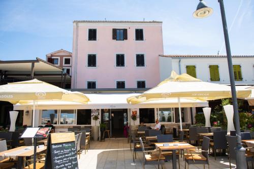 a restaurant with tables and umbrellas in front of a building at Hotel Marina in Fažana