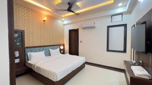 a bedroom with a bed and a flat screen tv at Hotel Abhinandan Palace in Udaipur